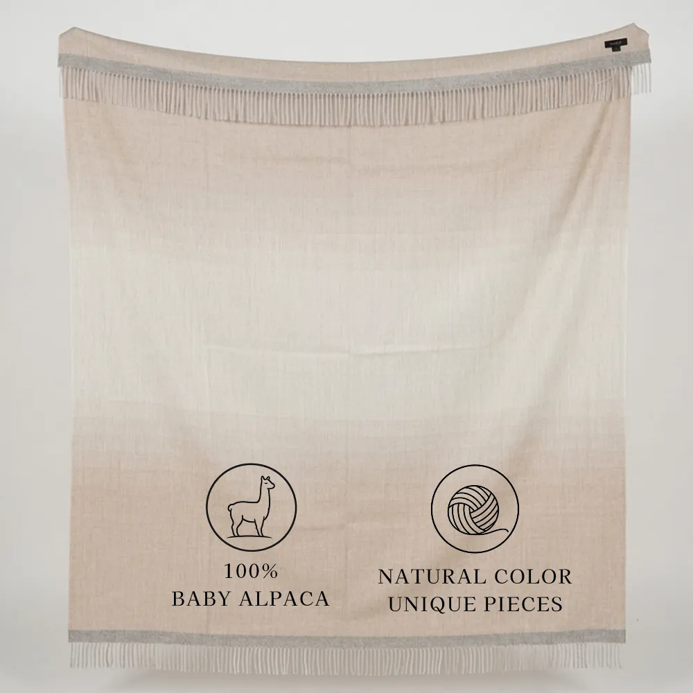 Cream-colored fringed alpaca blanket labeled “100% Baby Alpaca” and “Natural Color, Unique Pieces”