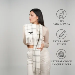 Model wearing a white-and-gray plaid scarf labeled 100% baby alpaca, extra-soft touch, and natural color unique pieces
