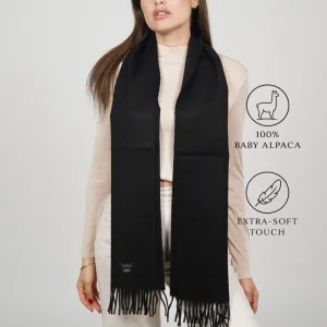 Model wearing a black fringed alpaca scarf labeled 100% BABY ALPACA and EXTRA-SOFT TOUCH