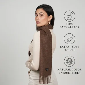 Model wearing a chocolate brown scarf labeled 100% baby alpaca, extra-soft touch, natural color, unique pieces