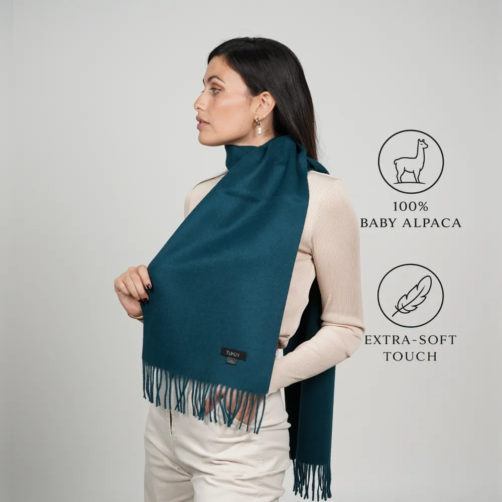 mujer con bufanda de alpaca verde azulado con flecos; etiquetado 100% baby alpaca y tacto extra suave