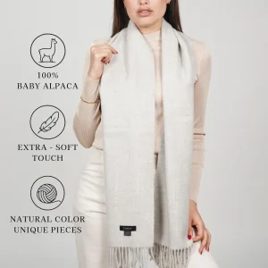 Model wearing a light-colored scarf labeled “100% baby alpaca,” “extra-soft touch,” and “natural color.”