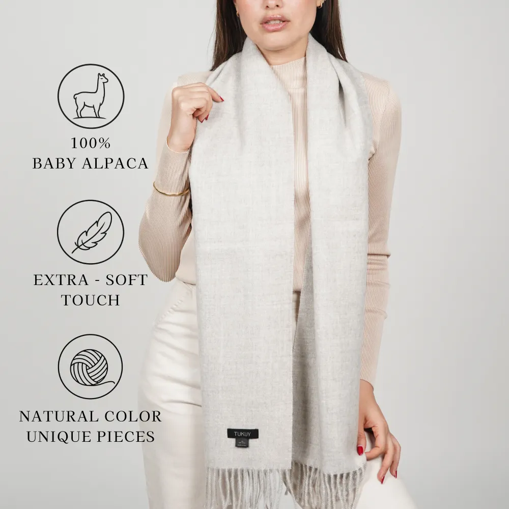 Model wearing a light-colored scarf labeled “100% baby alpaca,” “extra-soft touch,” and “natural color.”