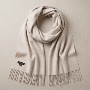 Baby alpaca scarf in oatmeal folded on a neutral background with fringe details