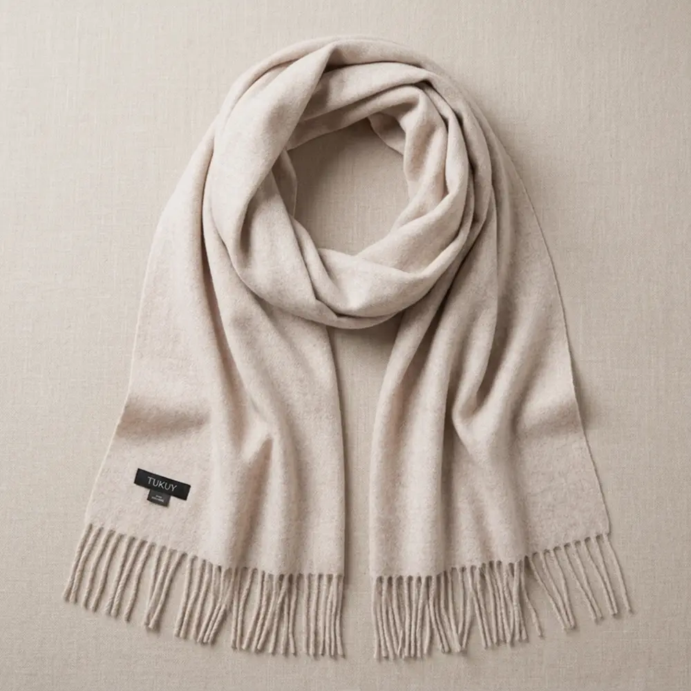 Baby alpaca scarf in oatmeal folded on a neutral background with fringe details