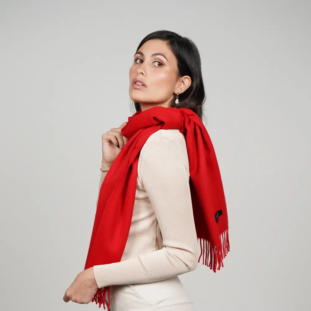Baby alpaca scarf in red worn over the shoulder by a woman