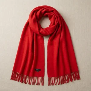 Baby alpaca scarf in red hanging on a neutral background showcasing its elegant design