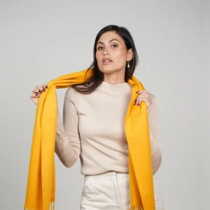 Baby alpaca scarf in mustard yellow worn over the shoulders by a woman