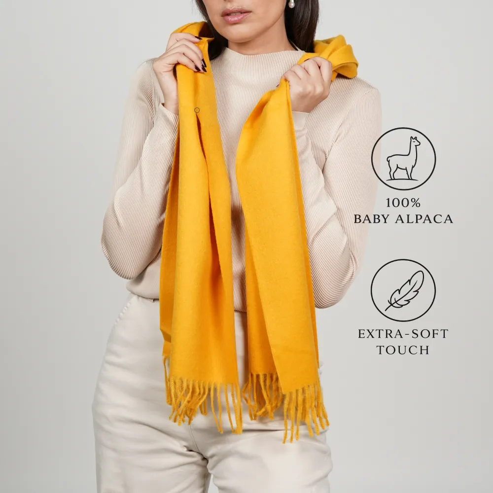 Model wearing a yellow scarf labeled “100% baby alpaca” and “extra-soft touch.”