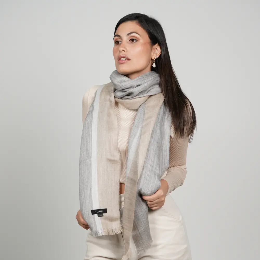 Baby alpaca shawl in grey and brown worn with a cream sweater showcasing its elegant design