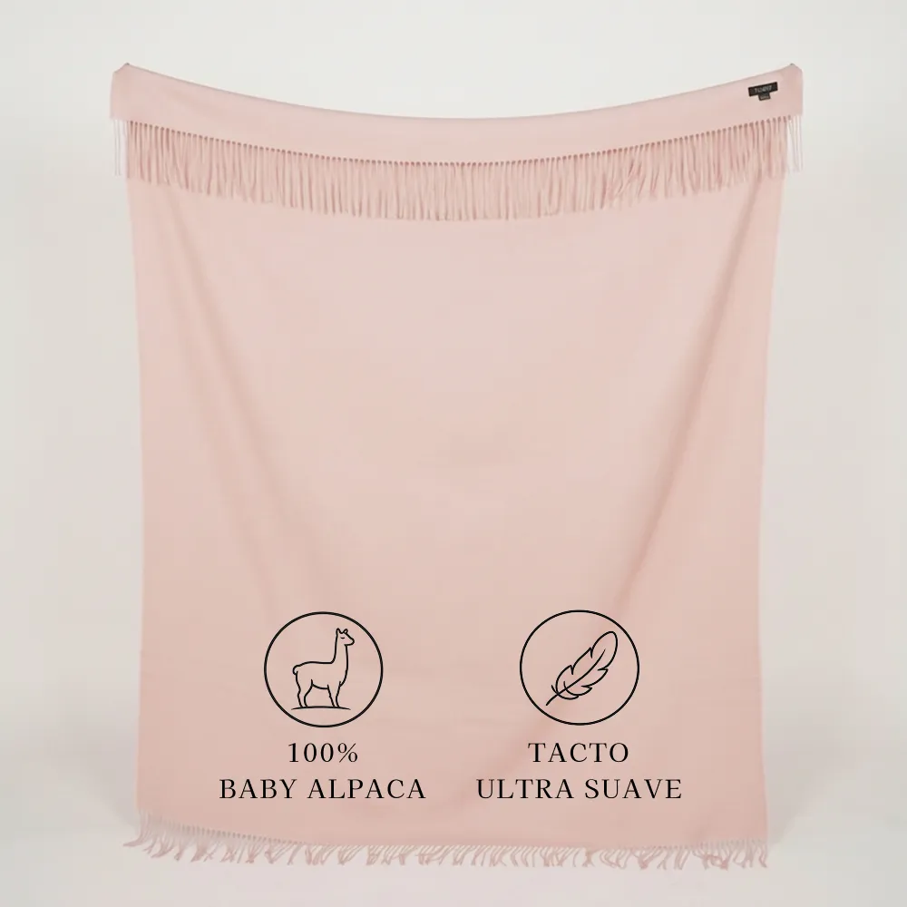Manta de baby alpaca rosa pastel extendida con flecos y textura suave