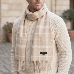 Man wearing a beige check alpaca scarf featuring a timeless windowpane pattern in soft beige and cream tones