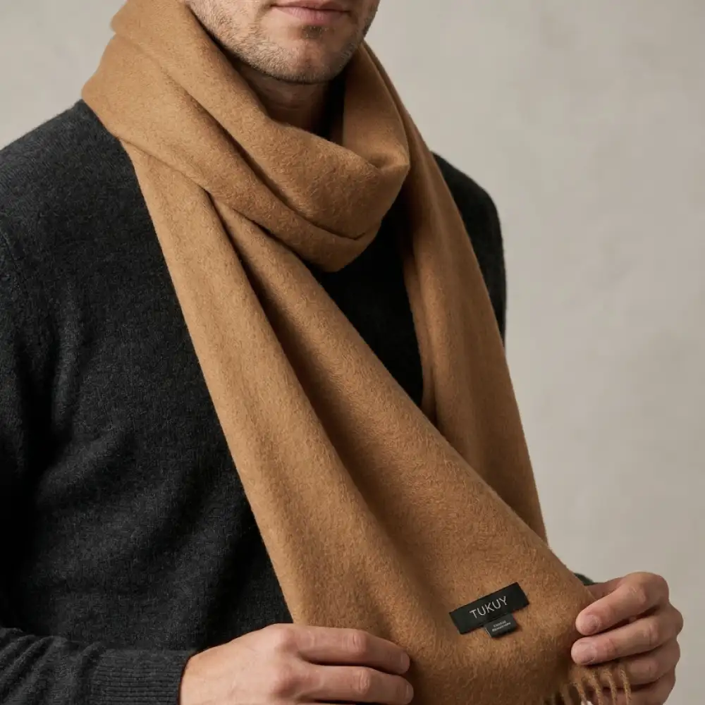 Men wearing a camel alpaca wool scarf in a natural camel color, paired with a charcoal sweater for a timeless winter look.
