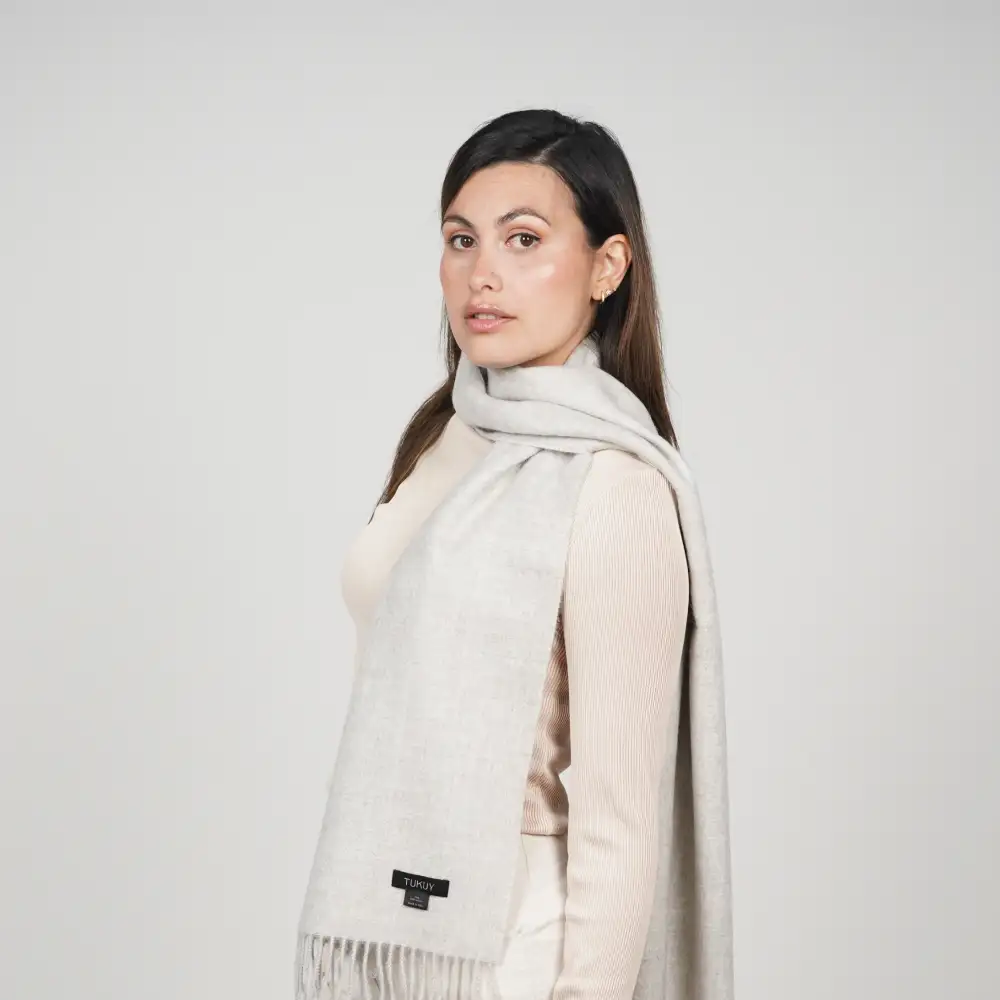 Woman styling the Ayllu light gray alpaca scarf, a timeless accessory crafted from natural baby alpaca wool.