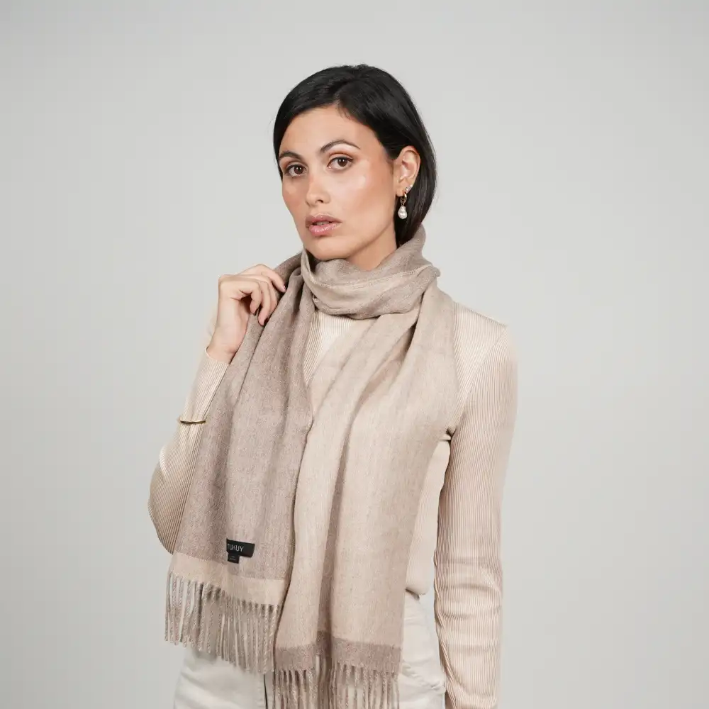 Woman wearing a reversible alpaca wool scarf in natural beige and taupe tones, showcasing its soft texture, elegant drape, and timeless neutral styling.